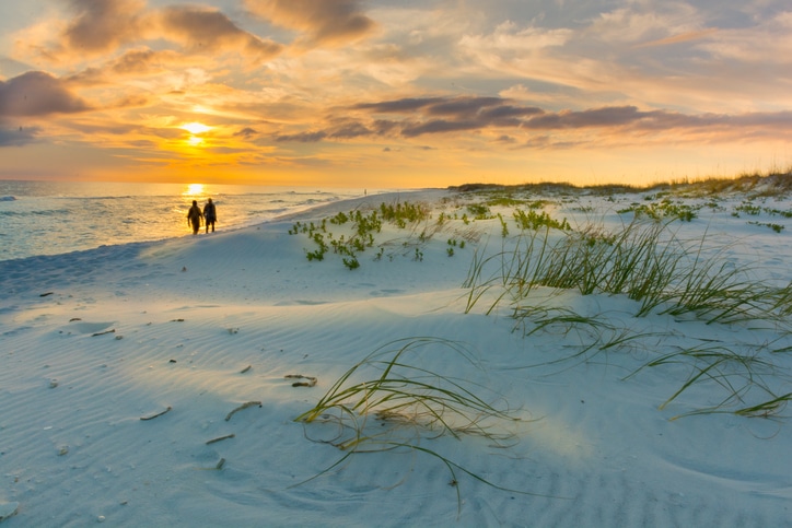 Couple walks on beach at sunset in st. johns county
