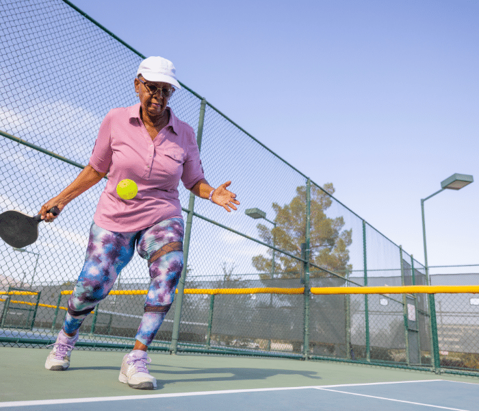 Older woman playing pickleball outside
