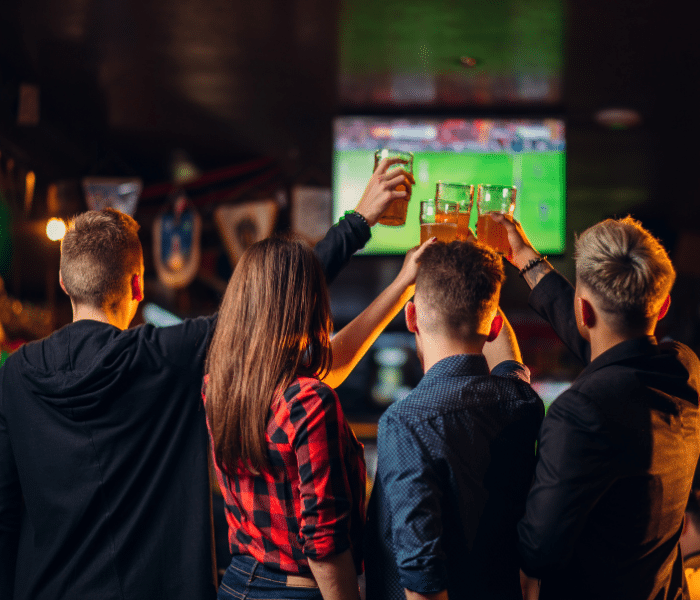 Four adults at a sports bar watching footbal