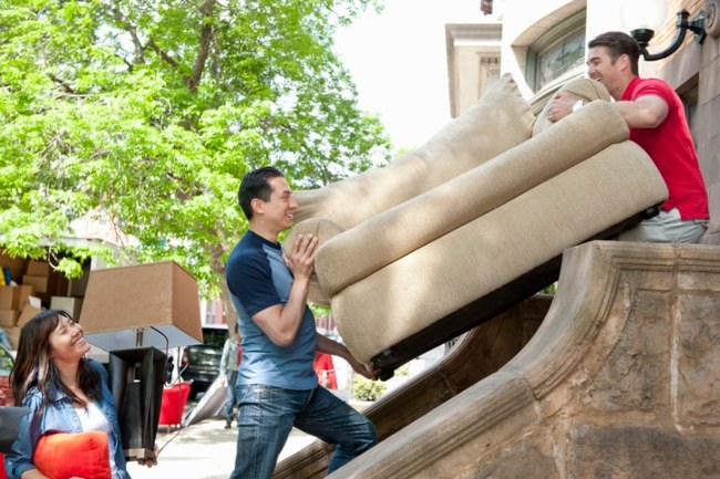 Two Men Moving a Sofa on a Staircase