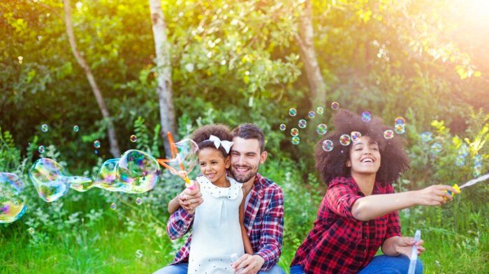 Happy Family Playing Soap Bubbles in Park