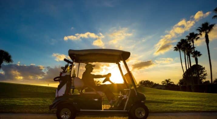 A Man Is Riding a Golf Cart Along the Pathway.